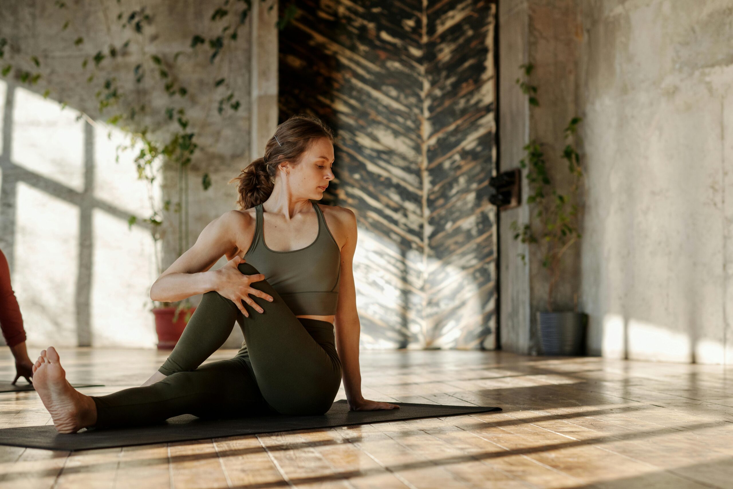 Une femme en posture de yoga en torsion sur son tapis de yoga