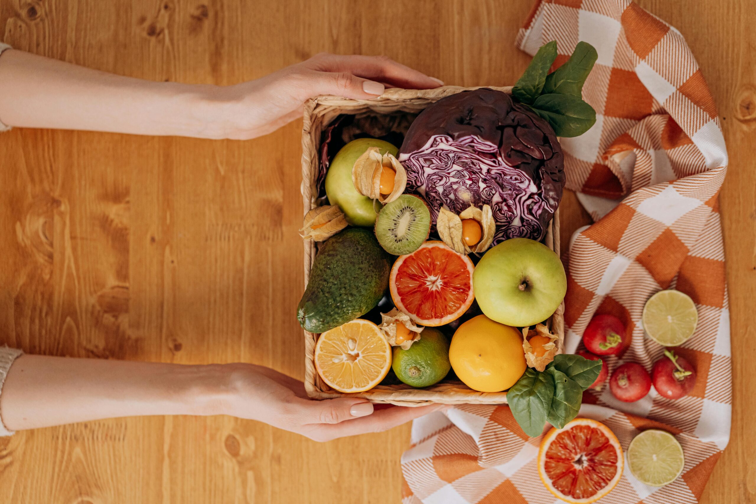 Une corbeille avec des fruits et des légumes tenue par les mains d'une femme