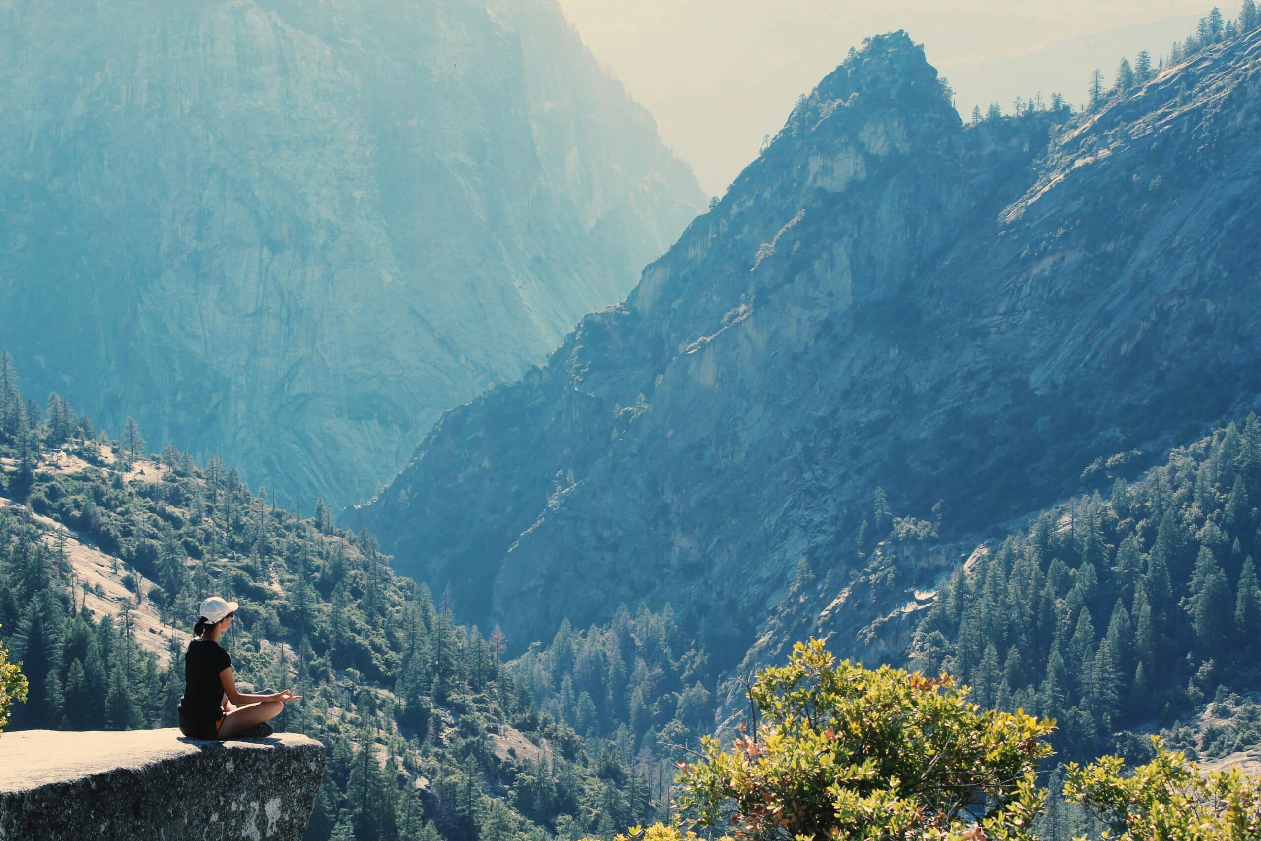Une femme assise en tailleur, les mains en gyan mudra dans la montagne, regardant au loin.